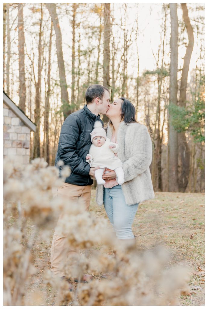 Winter Family Photos at Sugarloaf Mountain in Maryland - couple kissing and holding baby girl